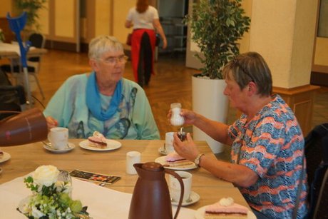 Zwei Frauen sitzen bei Kaffee und Kuchen an einem Tisch.