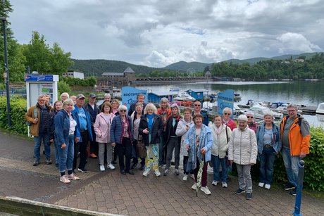 Reisegruppe vor dem Edersee mit Staumauer im Hintergrund