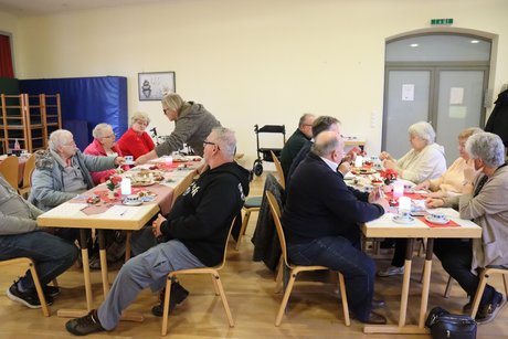 Mitglieder sitzen an gedeckten Tischen.