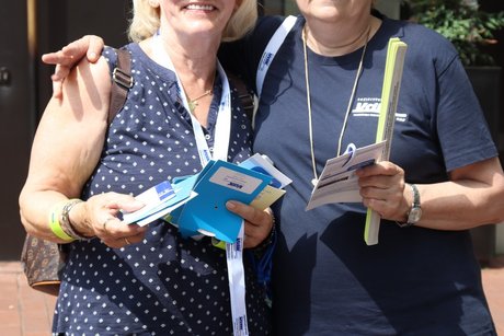 2 Frauen stehen zusammen, mit VdK Flyern in den Händen.