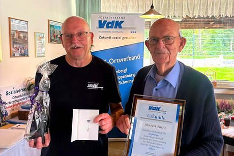 Jubilars- und Ehrenamts-Verleihung des VdK-Ortsverbandes Essen - Katernberg - Stoppenberg - Schonnebeck. Zwei Männer stehen nebeneinander für ein Foto mit Urkunde, Ehrennadel und Präsent.