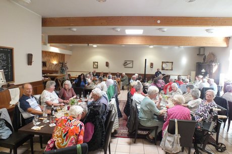 Mehrere Menschen sitzen an langen Tischen.
