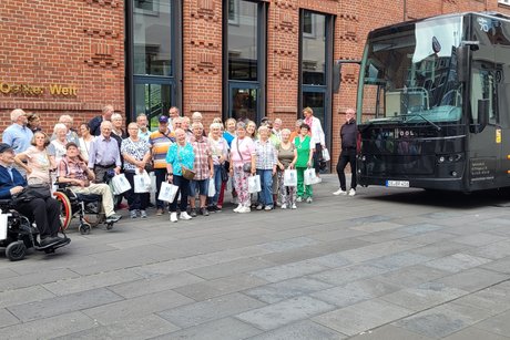 Hier stehen die Teilnehmer der Fahrt vor der Dr. Oetker Welt in der Gruppe. Rechts daneben der Bus.
