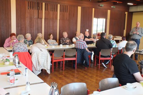 Mehrere Menschen sitzen an langen Tischen.