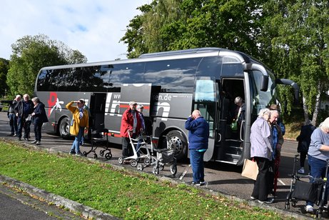 Ein Reisebuss aus dem Personen aussteigen und viele mit Rollator