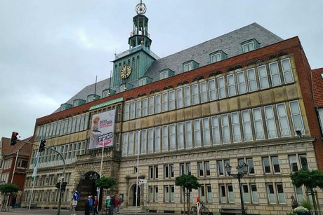 Beeindruckende Außenfassade des großen, von einem Kupferturm mit Uhr gekrönten Rathauses von Emden.