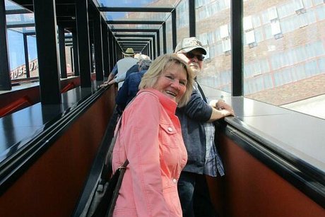 Menschen fahren auf einer Glas verkleideten langen Rolltreppe nach oben