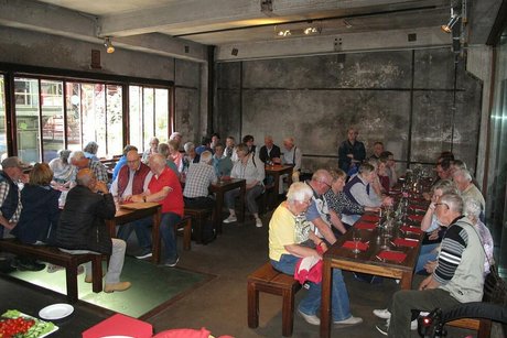 Menschen sitzen gemeinsam an Tischen in einem ehemaligen Zechengebäude.