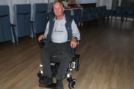 Ein Mann f&auml;hrt mit einem elektrischen Rollstuhl durch den Raum.