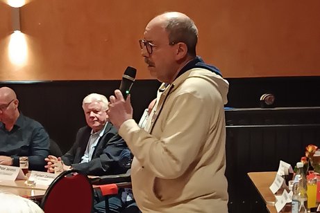 Auf dem Bild sieht man einen Mann mit Mikrofon der eine Ansprache f&uuml;r die Mitglieder h&auml;lt