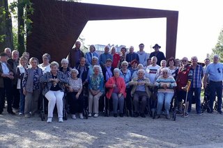 Das Bild zeigt die Besuchergruppe vor einem Denkmal aus Stahl