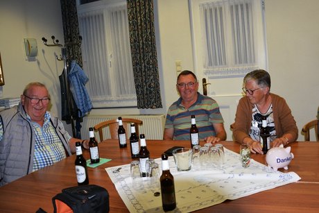 drei Personen sitzen am Tisch und lachen beim Bier