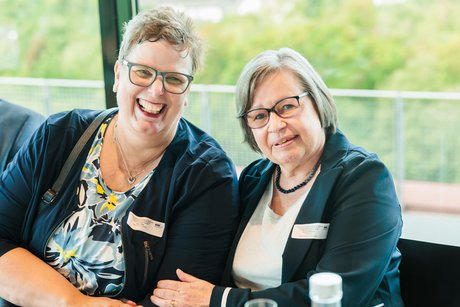 2 Frauen sitzen an einem Tisch.