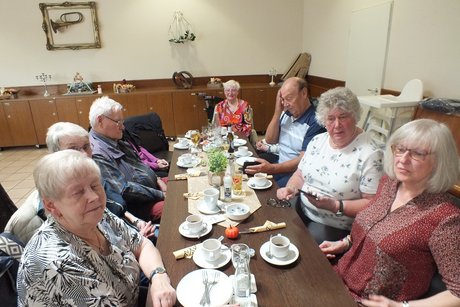 Mehrere Teilnehmer sitzen an langen Tischen.