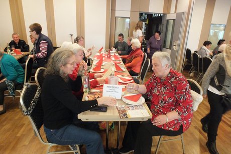 Mehrere Menschen sitzen an festlich gedeckten Tischen.