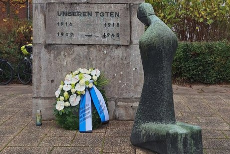 knieende Frau vor Ehrenmal mit Kranz des VdK