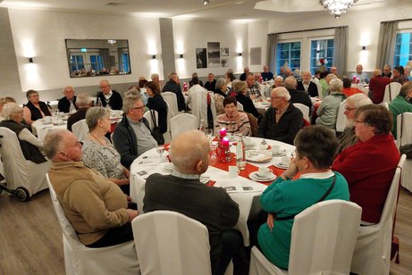 Viele Senioren sitzen an adventlich gedeckten Tischen im Festsaal des Hotel Meyerink.