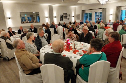 Viele Senioren sitzen an adventlich gedeckten Tischen im Festsaal des Hotel Meyerink.