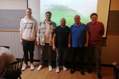 Gruppenfoto der Mitarbeiter des Pflegediensts 4life vor einer Leinwand mit Beamer-Präsentation