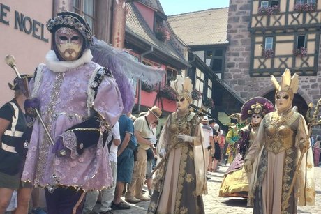 Prächtige venezianische Karnevalsköstüme vor historischer Kulisse in Riquewihr.