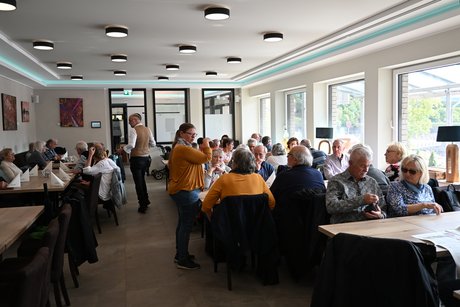 Mittagessen Ein großer Saal. Die Reisenden sitzen an Tischen und arten aufs Mittagessen