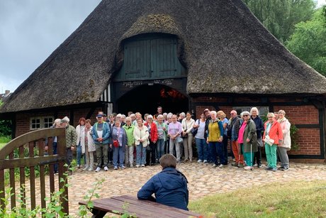 Gruppenbild Menschen in einer Gruppe vor einer Räucherkate