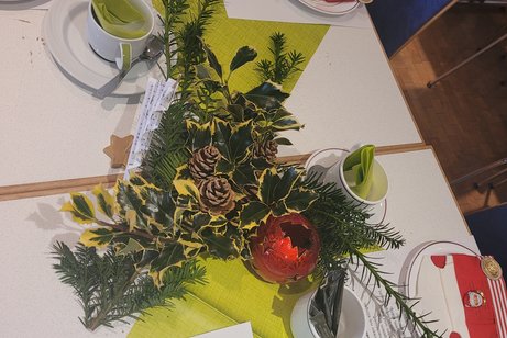 Ein gedeckter Tisch mit Schokoladennikolaus und weihnachtlichen Gesteck und roten Servietten