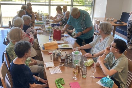 Menschen sitzen an einem langen Tisch und spielen Bingo.