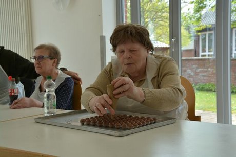 Vorsichtig füllt eine Teilnehmerin Ganache in Hohlraumkugeln aus Vollmilchschokolade.