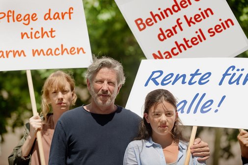 Demo für soziale Gerechtigkeit Gruppe von Menschen verschiedenen Geschlechts und Alters, mit und ohne Behinderung, demonstrieren. Auf den Demopappen steht "Pflege darf nicht arm machen", "Behinderung darf kein Nachteil sein" und "Rente für alle"