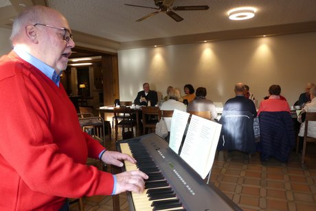 Hans-Werner Füchtmann am Keyboard stimmt Weihnachtslieder an Im Vordergrund Herr Füchtmann am Keyboard, im Hintergrund Personen an Tischen