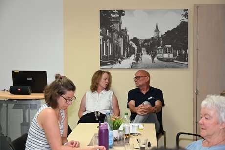 Menschen sitzen am Tisch bei einer Unterhaltung