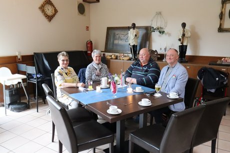 Frühlingsfest Zwei Frauen und zwei Männer sitzen an einem Tisch und lächeln in die Kamera.