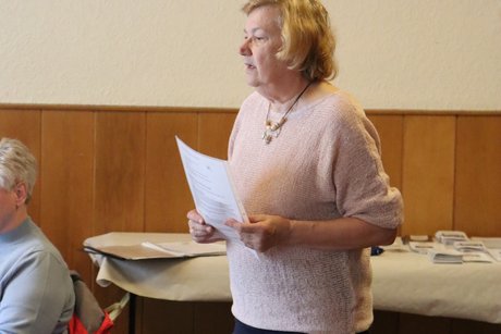 Jahreshauptversammlung 2026 Eine Frau steht im Raum mit einem Zettel in der Hand und spricht zu der Gruppe.