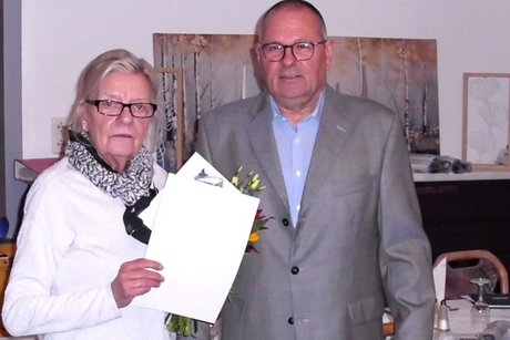 Ein Mann überreicht eine Urkunde an eine Frau.