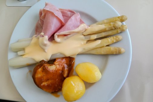Auf dem Bild sieht man einen gef&uuml;llten Teller mit Spargel, Kartoffeln gek. Schinken und einem Schweinemedaillon
