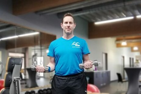 Ein Mann mit Hanteln steht in einem Fitness-Raum