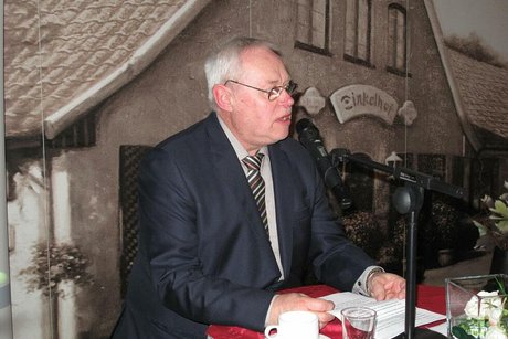 Ein Mann in dunklem Anzug steht an einem Stehtisch mit Mikrofon und hält eine Rede.