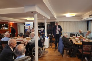 Klaus Meiers bei der Begrüßung zwischen den Mitgliedern im Saal von Café Mauritius