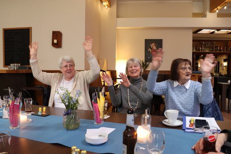 Frühlingsfest Drei Frauen sitzen nebeneinander und bewegen die hochgehobenen Arme im Rhythmus der Musik hin und her.