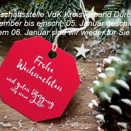 Weihnachszeit Tannenzweige, Christbaumkugeln und ein rotes Schild mit weißer Schrift: Frohe Weihnachten.