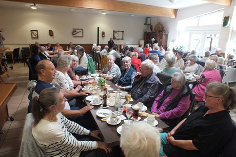 Mehrere Menschen sitzen an langen Tischen.