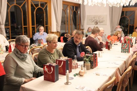 Mehrere Menschen sitzen an gedeckten Tischen.