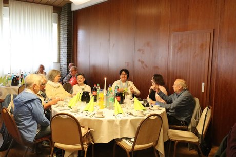 Mehrere Personen sitzen an einem gro&szlig;en runden Tisch.