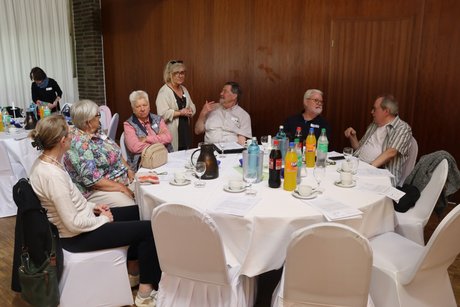 Mehrere Personen sitzen an einem runden Tisch.