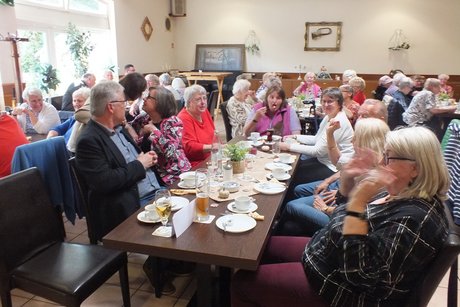 Mehrere Menschen sitzen an langen Tischen.