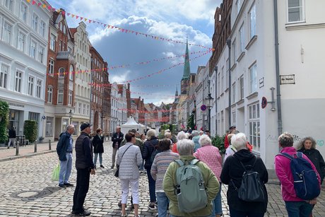 Altstadt Lübeck Menschen bei einer Stadtführung in der Altstadt mit Blick auf eine Kirche
