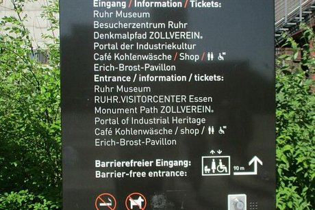 Eine Informationstafel auf dem Außengelände der Zeche Zollverein weist auf die Kohlenwäsche und die barrierefreien Eingänge zur Ausstellung hin.