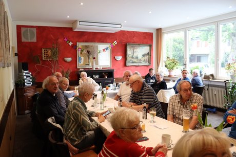 Mehrere Personen sitzen an langen Tischen.