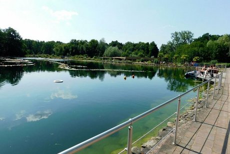 Uferpromenade mit Geländer entlang eines Teiches